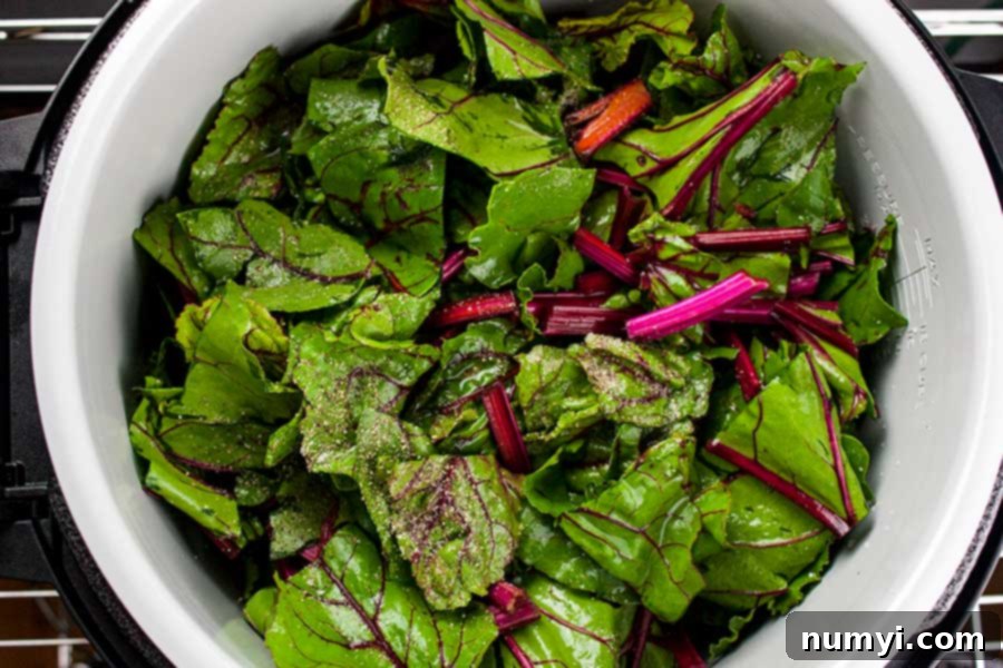 beet greens in the pot of the Ninja Foodi seasoned with salt and pepper