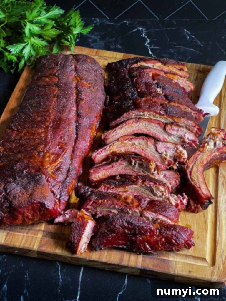 The Ultimate Smoked Baby Back Ribs 13 Two racks of baby back ribs, one of which is cut up on a wooden cutting board.