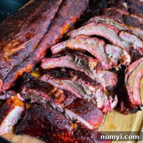 The Ultimate Smoked Baby Back Ribs 14 Memphis style baby back ribs laid on on a wooden cutting board.