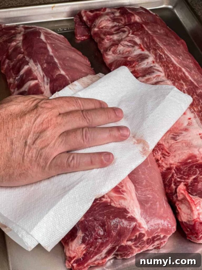 The Ultimate Smoked Baby Back Ribs 5 Drying baby back ribs off with a paper towel.