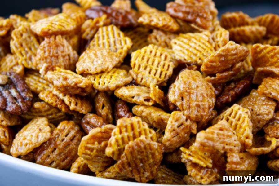 A delicious bowl of Praline Crunch Snack Mix, showcasing the golden caramel-coated cereal and pecans.