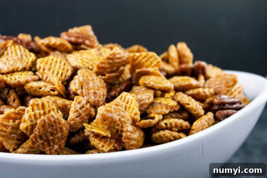 Closeup of the Praline Crunch Snack Mix in a white serving bowl, showing the texture and golden coating.