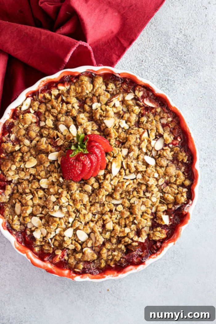 Overhead view of strawberry crisp fresh from the oven with a fresh strawberry fanned out on top for garnish.