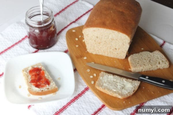 Wholesome Whole Wheat Oatmeal Bread 3 Whole Wheat Oatmeal Bread on a cutting board with a few slices around. one is on a plate with butter and jam, and a jam jar sitting next to it