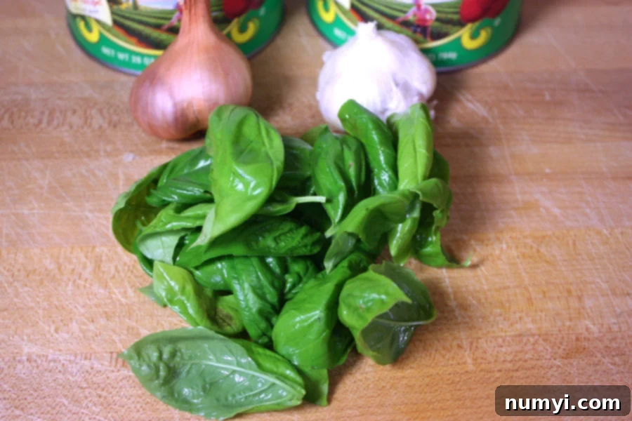 Effortless Creamy Tomato Basil Soup 3 Fresh basil, garlic, and shallot on a wooden board.