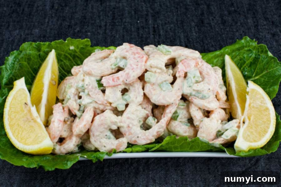Easy Shrimp Salad 5 Shrimp salad on a lettuce lined white platter garnished with lemon wedges.