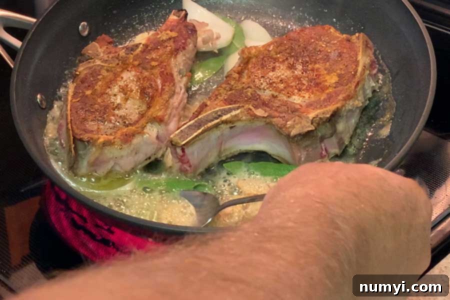 Basting pork chops in a skillet with aromatic sage and butter sauce.
