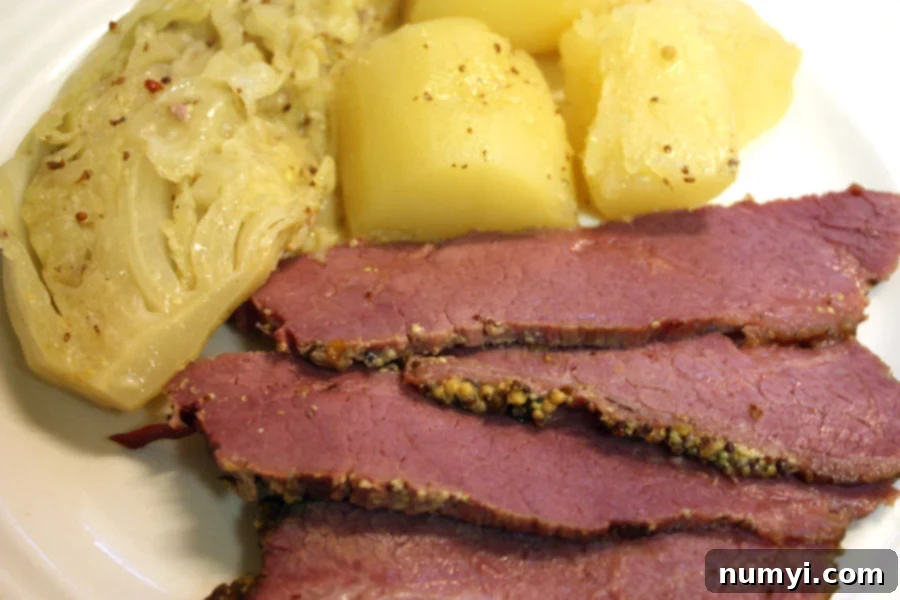 Corned Beef with Mustard Sauce beautifully plated with potatoes and cabbage.