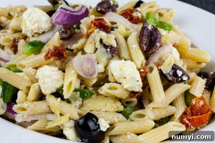Zesty Greek Pasta Salad 2 A vibrant Greek Pasta Salad served in a white ceramic bowl, showcasing colorful vegetables, feta, and pasta.