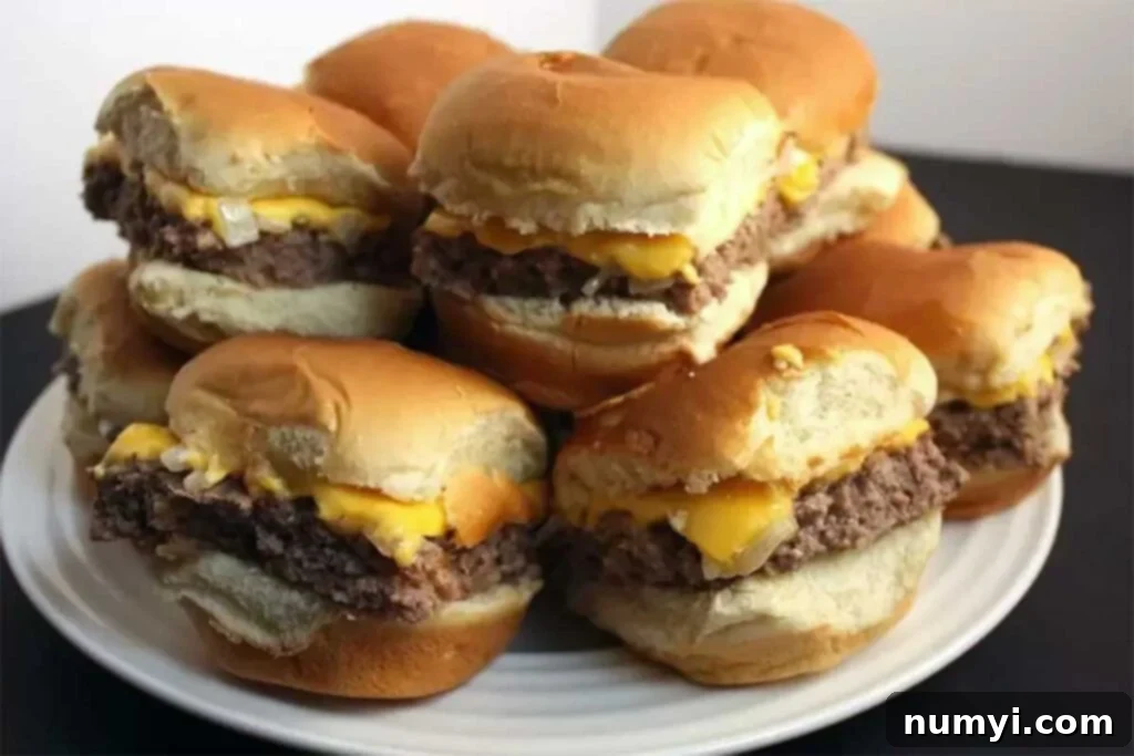 Ultimate Oven Cheeseburger Sliders 2 Oven Baked Sliders stacked up on a white plate, showcasing the perfectly melted cheese and golden buns, ready to be enjoyed.