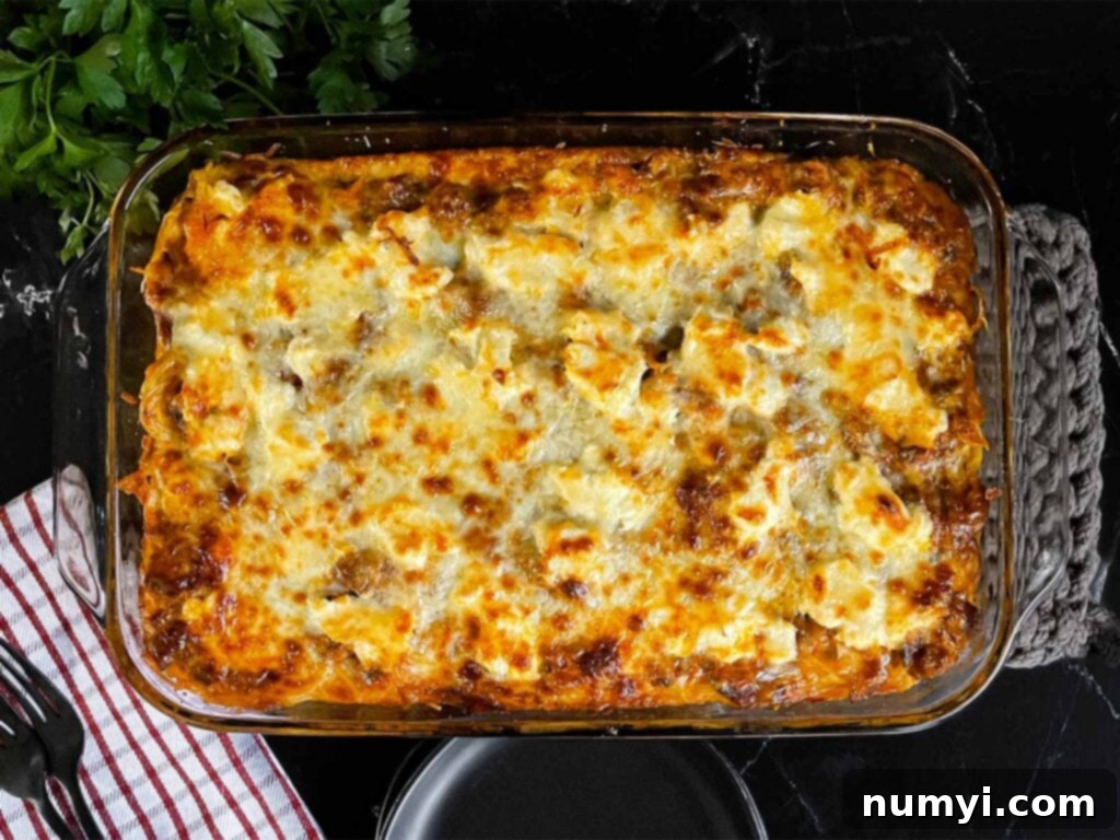 Baked spaghetti in a glass baking dish on a dark surface.
