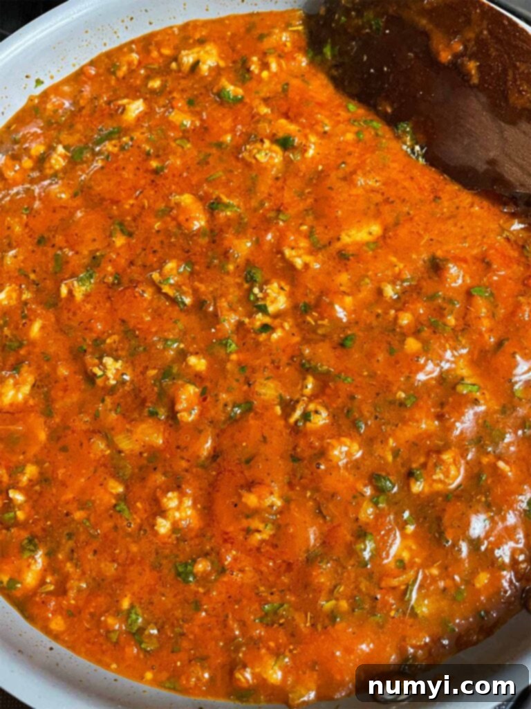 Marinara sauce with Italian sausage for baked spaghetti cooking in a large skillet.
