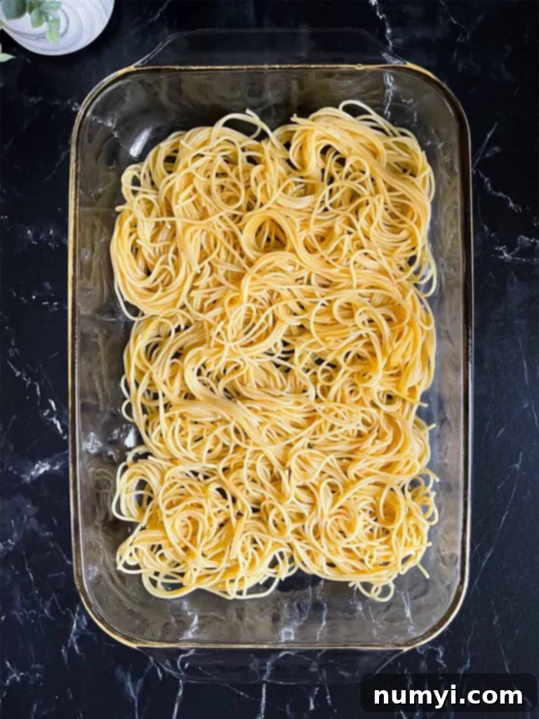First layer of noodles in a glass baking pan for baked spaghetti.