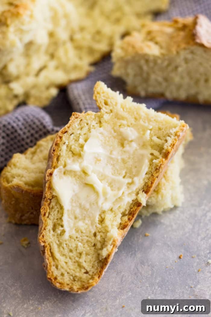 A delicious slice of warm Irish Soda Bread, generously buttered and ready to enjoy.