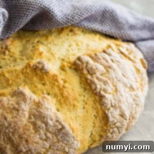 Round loaf of Traditional Irish Soda Bread wrapped in a towel.