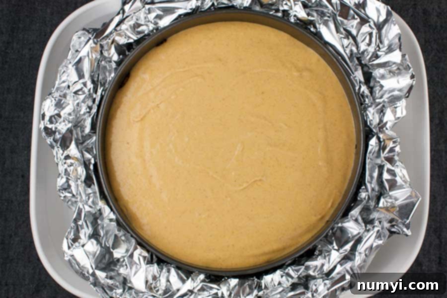 Cheesecake batter in the springform pan inside a water bath pan.