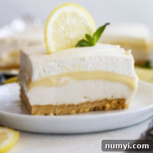 A piece of lemon dessert on a plate garnished with a lemon slice and mint.