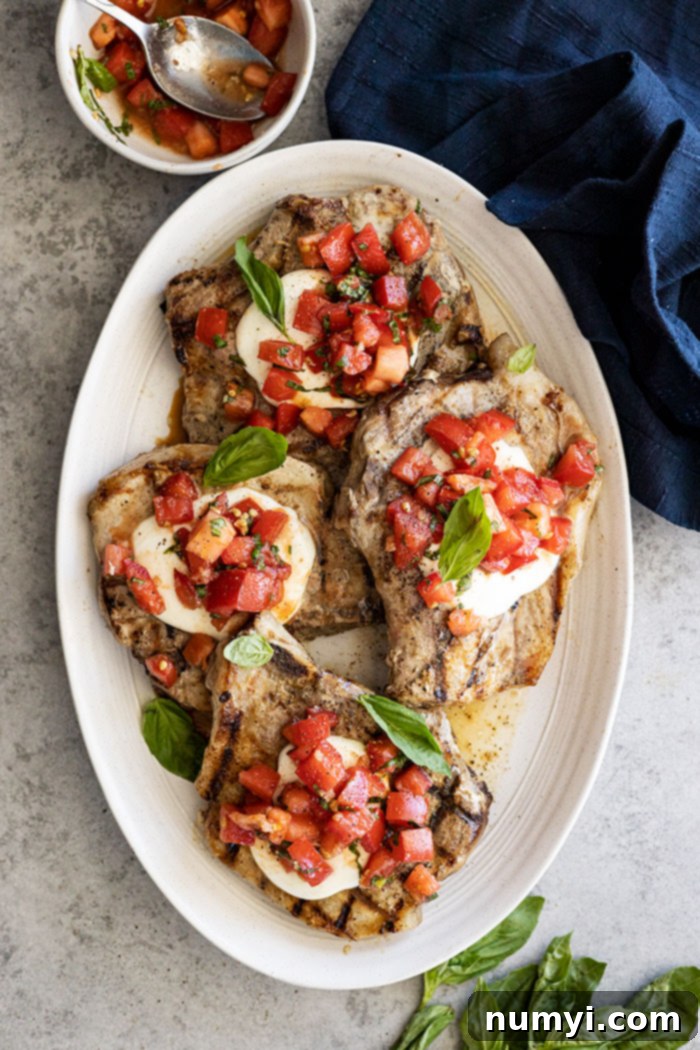 Flavorful Bruschetta Pork Chops 2 Overhead view of bruschetta pork chops on a serving platter garnished with fresh basil.