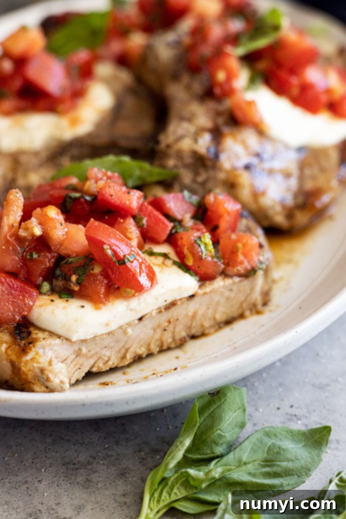 Flavorful Bruschetta Pork Chops 6 A pork chop with a slice taken out to show the juicy interior.