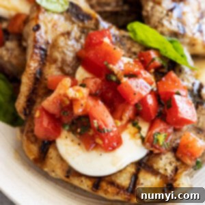 Flavorful Bruschetta Pork Chops 7 Close up of pork chop topped with melted mozzarella and bruschetta.