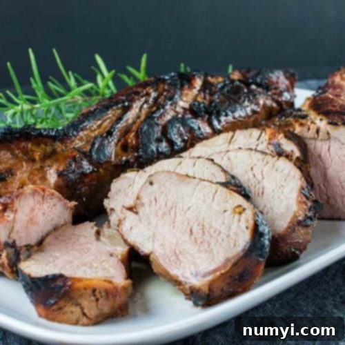 Your New Favorite Keto Grilled Pork Tenderloin 10 Keto grilled pork tenderloin sliced on a white platter garnished with fresh rosemary.