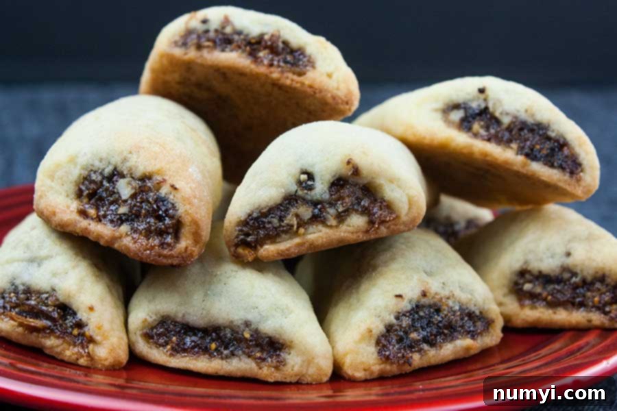 Italian fig cookies or Cucidati stacked on a red plate, glistening with a light glaze and topped with sprinkles.