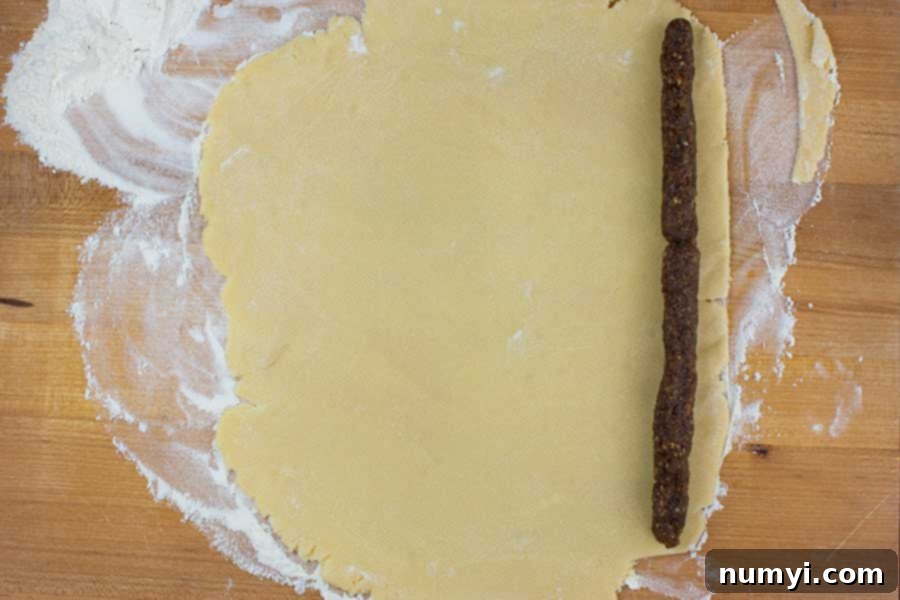 Fig filling rolled into thin ropes, placed on parchment paper, next to a portion of cookie dough.