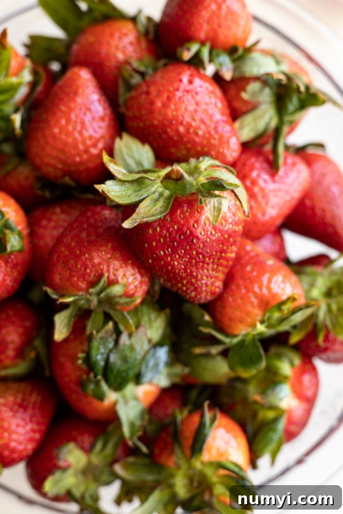 A large bowl filled with an abundance of red ripe strawberries, showcasing their freshness and vibrant color.
