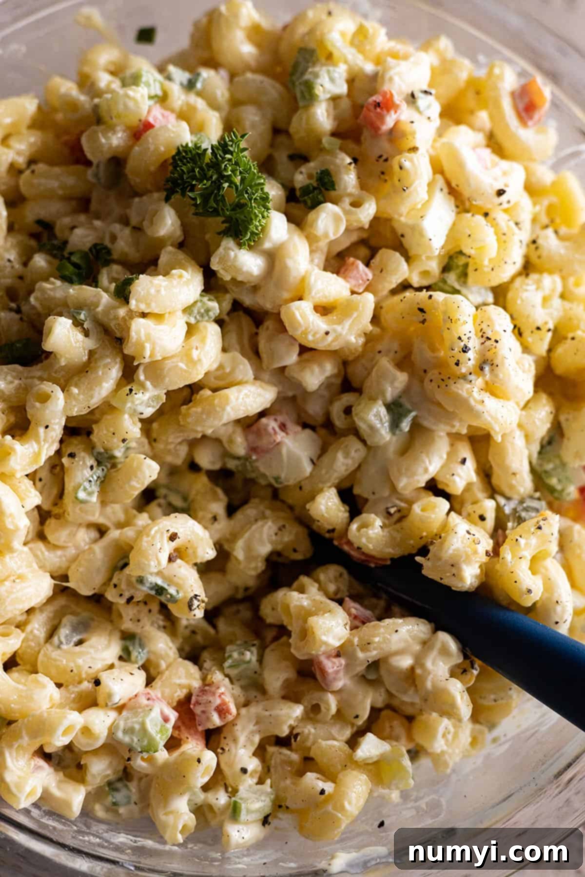 Close of up macaroni salad garnished with parsley and black pepper. 