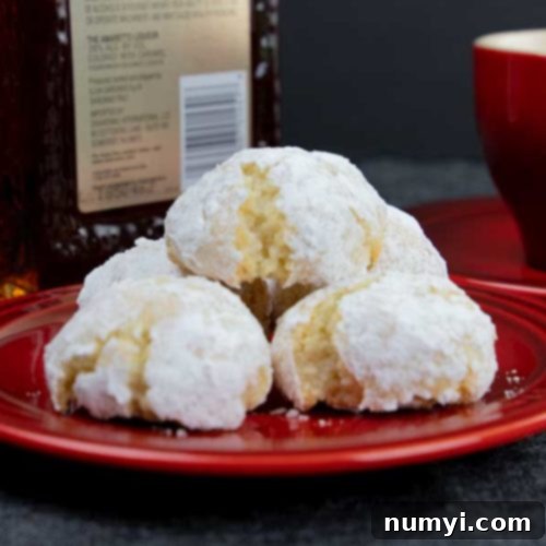 Amaretti cookies stacked on a red plate with a red coffee cup in the background.