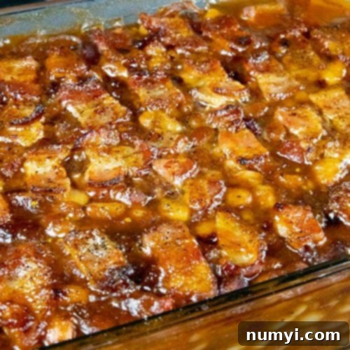 Baked Beans topped with bacon in a glass baking dish.