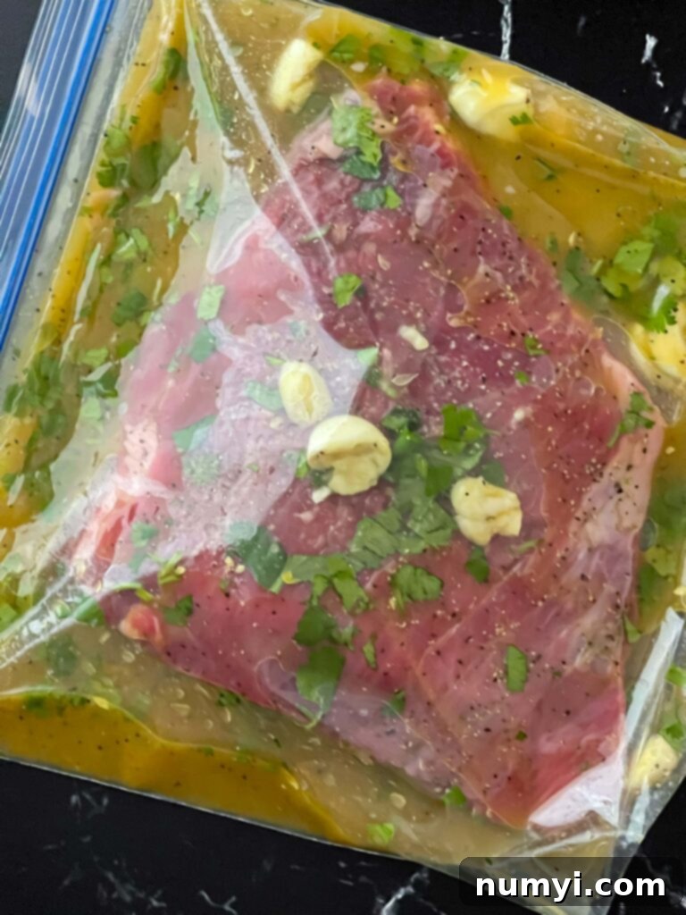 Flank steak submerged in a rich, vibrant marinade inside a container, ready for chilling.