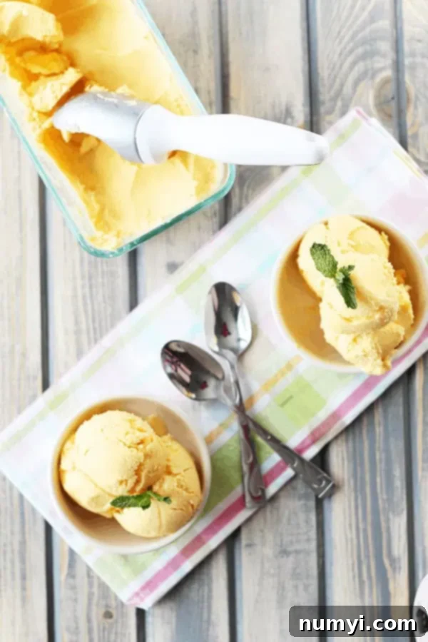 overhead: mango yogurt ice cream in freezer-safe container with ice cream scoop and two bowls of frozen yogurt in circular white dish 
