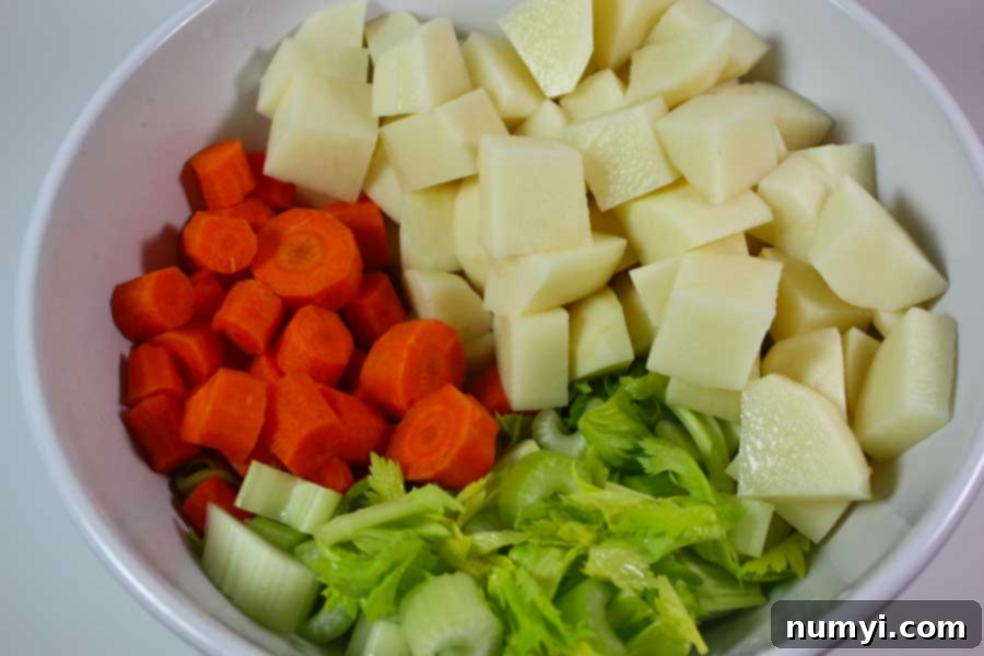 Diced potatoes, carrots, and celery in a white bowl.