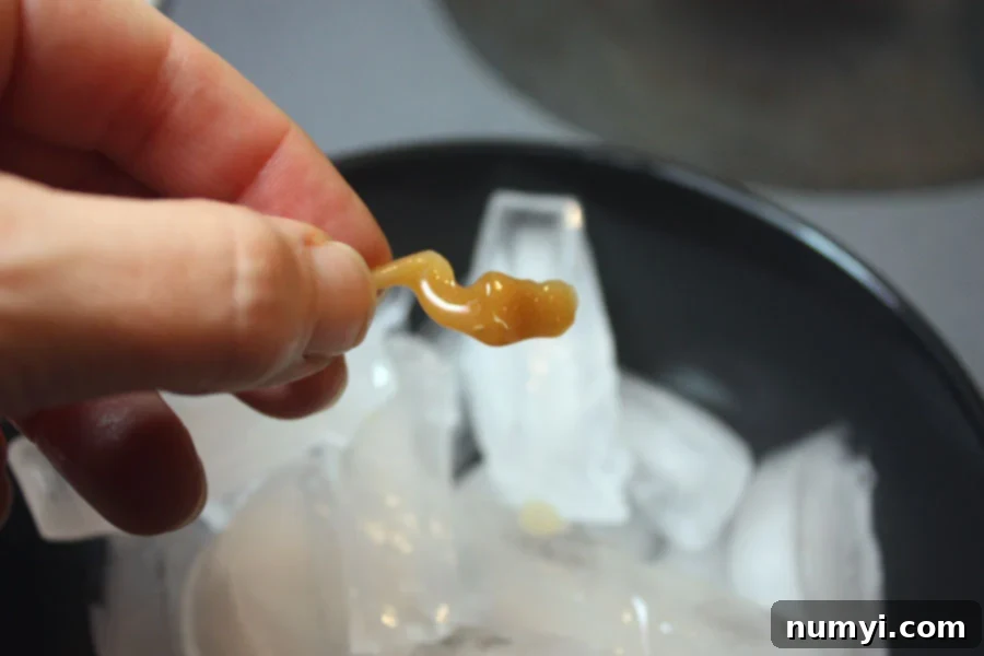 Piece of dripped hard candy being held over the ice.