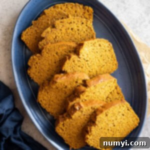 Overhead view of several slices of pumpkin bread staggered on a blue plate.