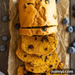Warm Spiced Pumpkin Blueberry Loaf 7 Overhead view of slices of pumpkin blueberry bread with blueberries scattered to the side.