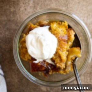Spiced Pumpkin Bread Pudding 6 Overhead view of pumpkin bread pudding in a glass bowl drizzled with caramel sauce and a dollop of whipped cream.