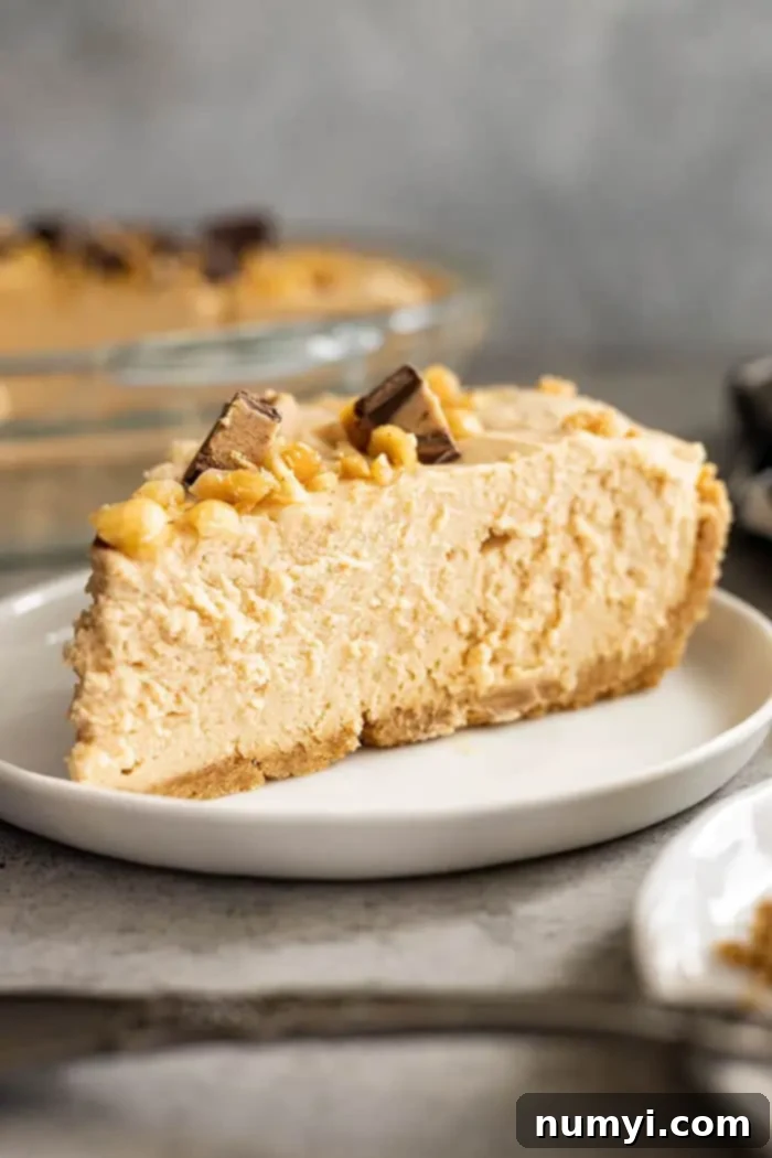 A pristine slice of creamy peanut butter pie, showing off its perfect layers and smooth texture, resting on a white plate ready to be enjoyed.