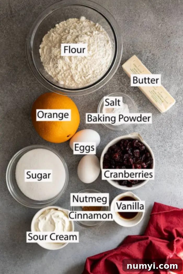 Zesty Cranberry Orange Muffins 3 A flat lay photograph displaying all the fresh ingredients for Cranberry Orange Muffins: all-purpose flour, butter, vibrant orange zest, fresh orange juice, salt, baking powder, eggs, granulated sugar, sour cream, ground nutmeg, cinnamon, vanilla extract, and plump cranberries.