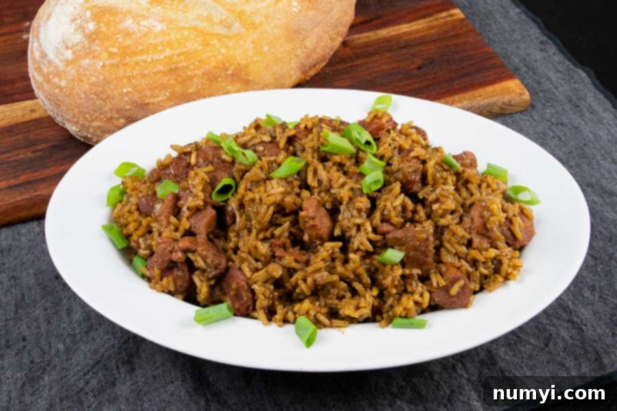 A close-up shot of a serving bowl filled with steaming Cajun jambalaya, accompanied by a slice of crusty sourdough bread.