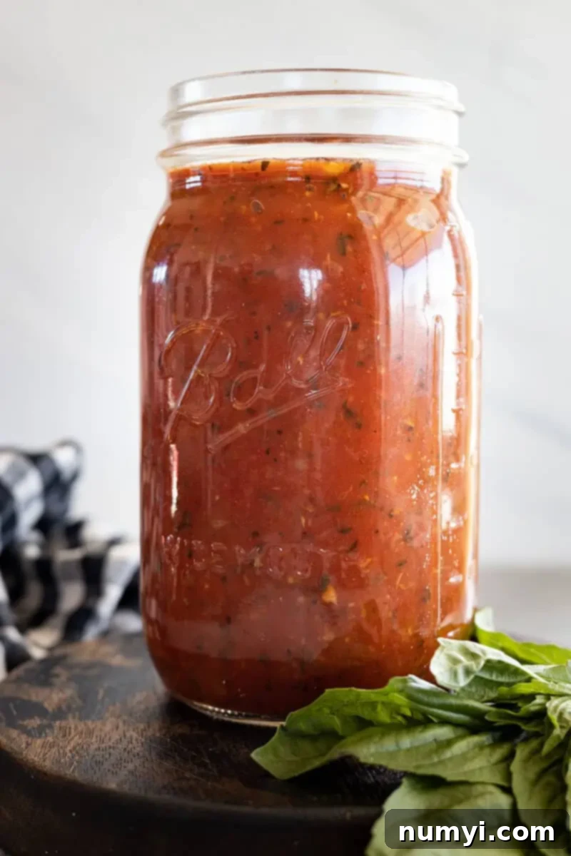 Marinara Sauce in a mason jar with a bunch of basil off to the side, ready to be used or stored.