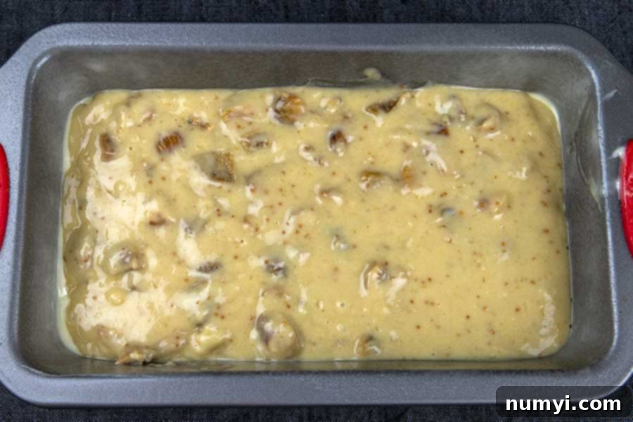 Walnut fig bread batter poured into a parchment-lined loaf pan, ready for baking.