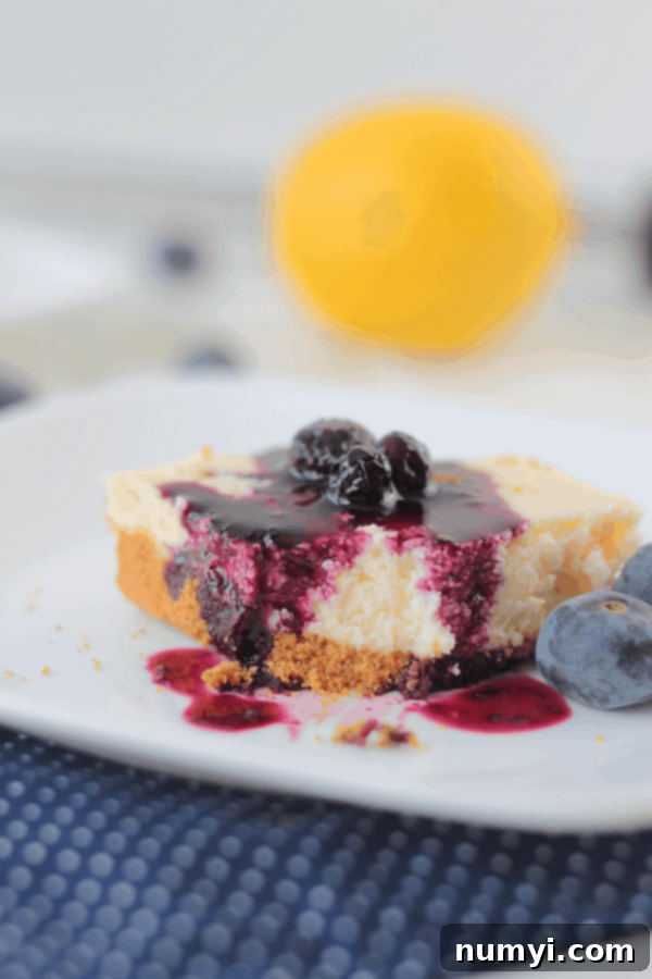 Zesty Lemon Cheesecake Bars 4 a lemon cheesecake bar with a bite taken out of it and blueberry topping drizzled on top