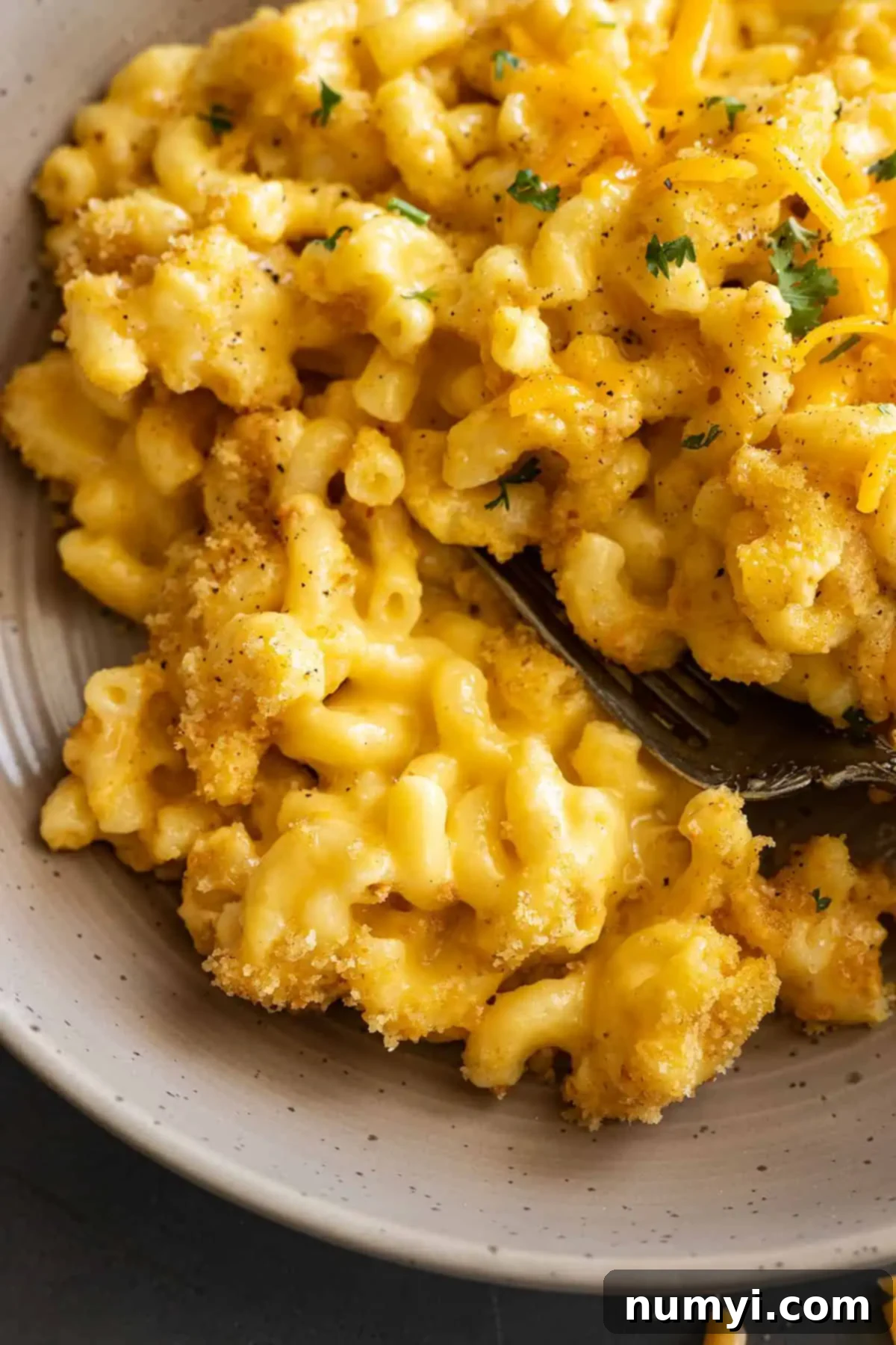 Close up of mac and cheese in a bowl with a fork in it.