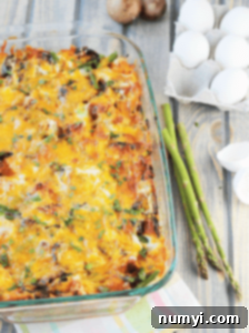 A baked mushroom and asparagus strata in a baking dish, with a slice already removed, ready to be served.