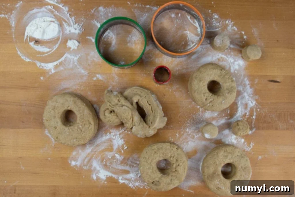 Apple cider donut dough cut out on wooden board.