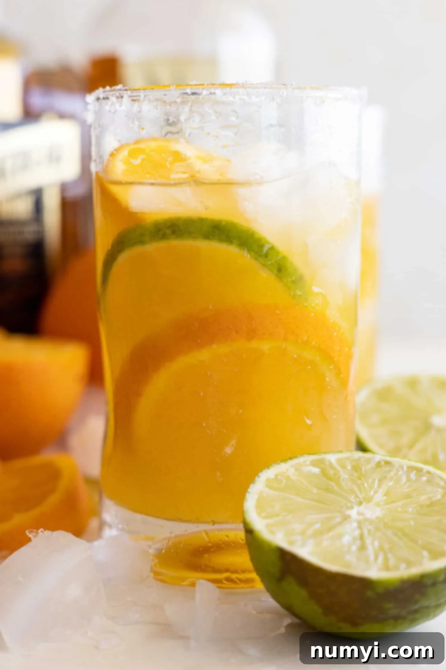 Zesty Orange Margarita 2 Glass of orange margarita with an orange and lime slice in it. Cut limes and oranges off to the sides.