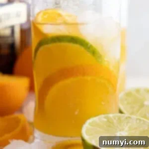 Zesty Orange Margarita 7 Glass of orange margarita with an orange and lime slice in it. Cut limes and oranges off to the sides.