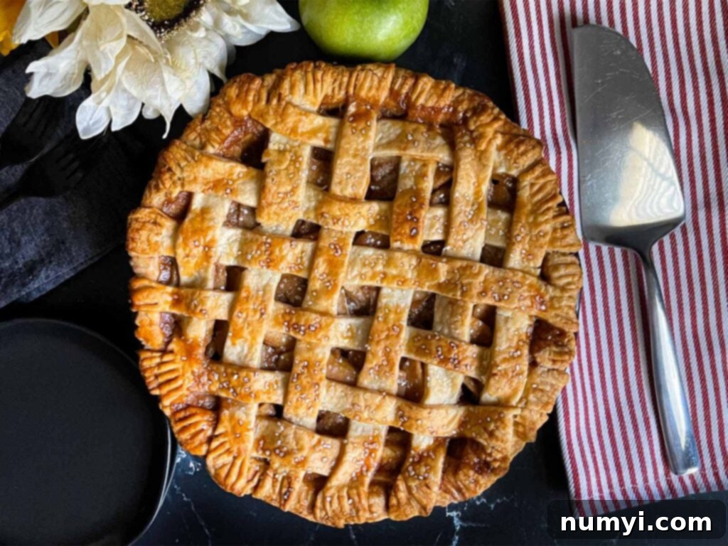 Lattice crust apple pie on a dark surface, perfectly golden brown.